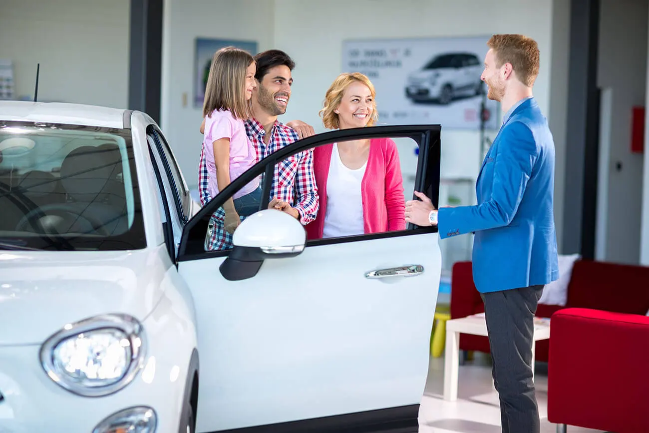 Family who have previously been declined car finance are in a showroom next to an open car they could be approved for