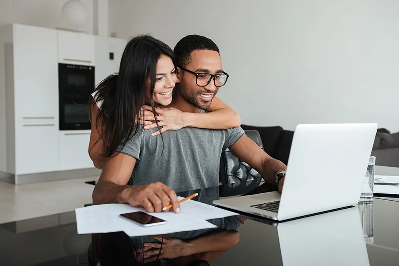 Happy couple looking at laptop applying for poor credit car finance