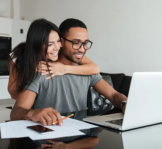 Happy couple looking at laptop applying for poor credit car finance