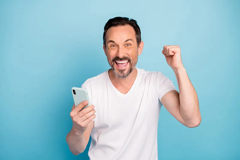 Man in white t-shirt happy with approval for car finance with defaults