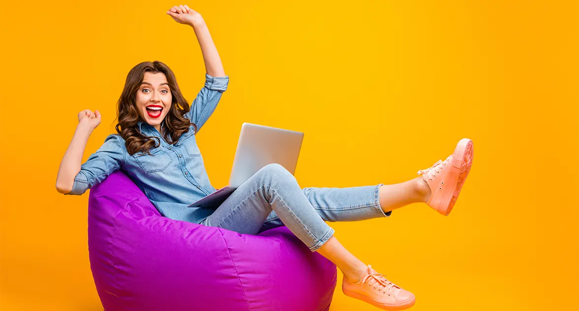 Woman sitting on bean bag with laptop happy with no guarantor car finance approval