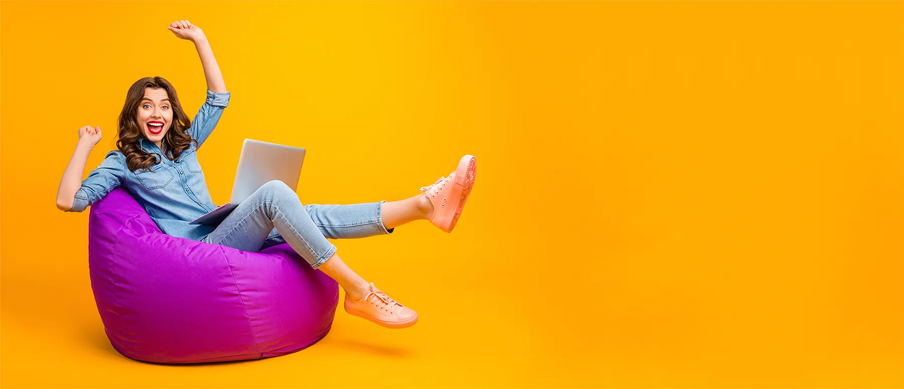 Woman sitting on bean bag with laptop happy with no guarantor car finance approval