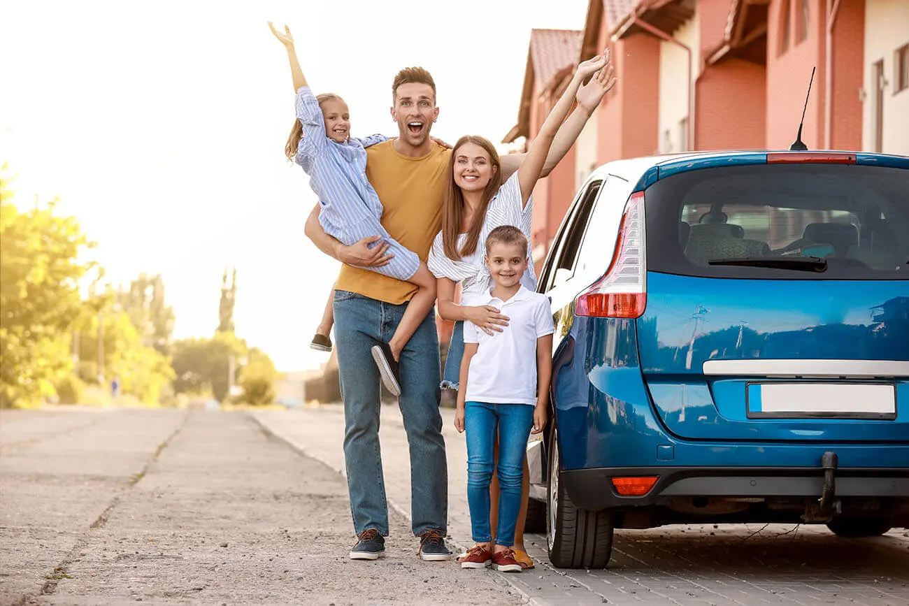 Young family waving whilst standing next to car purchased with used car finance